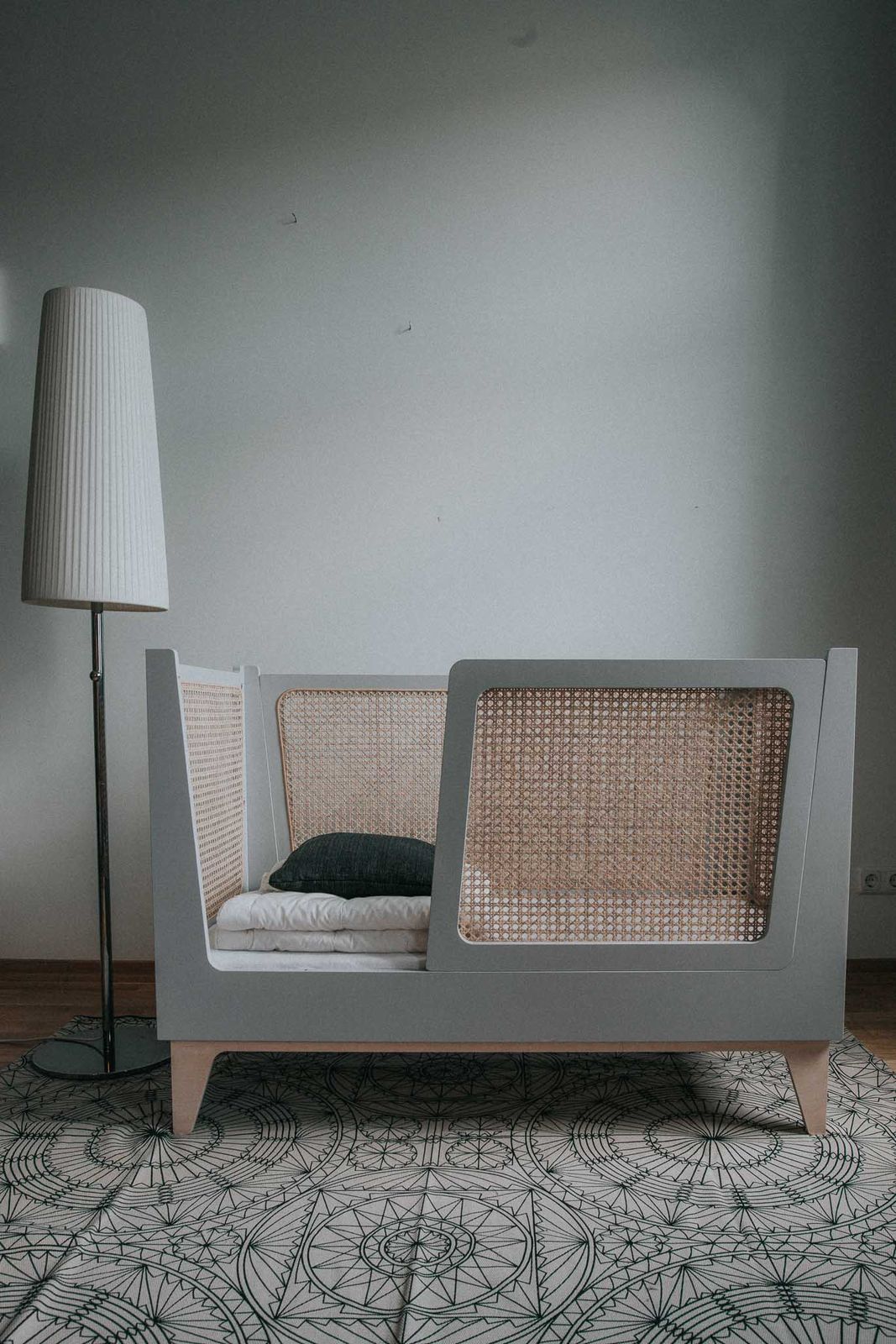 Kinderbett in Frontalansicht, Wiener Geflecht im Kopfteil, weiße Bettwäsche