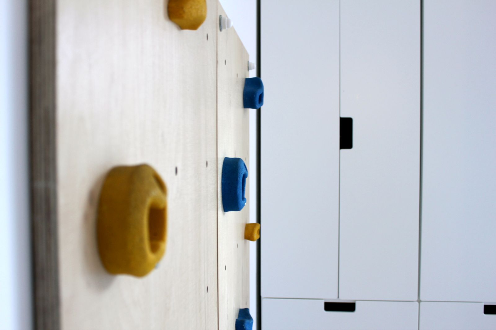 Indoor-Kletterwand mit farbigen Klettersteinen an heller Wand neben dem Hochbett