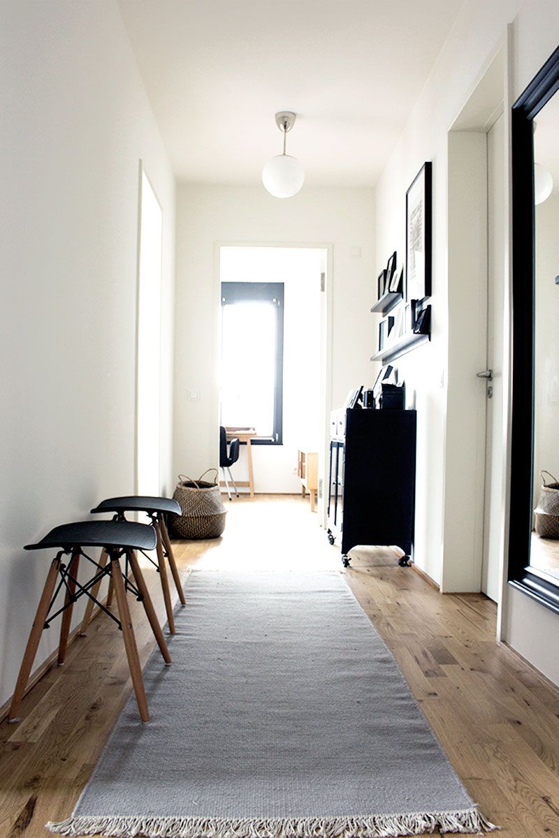 Schmaler Neubauflur mit warmem Licht, Garderobe und dezentem Spiegel an der Wand